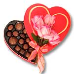 Photo of a heart shaped box of chocolates and four pink roses